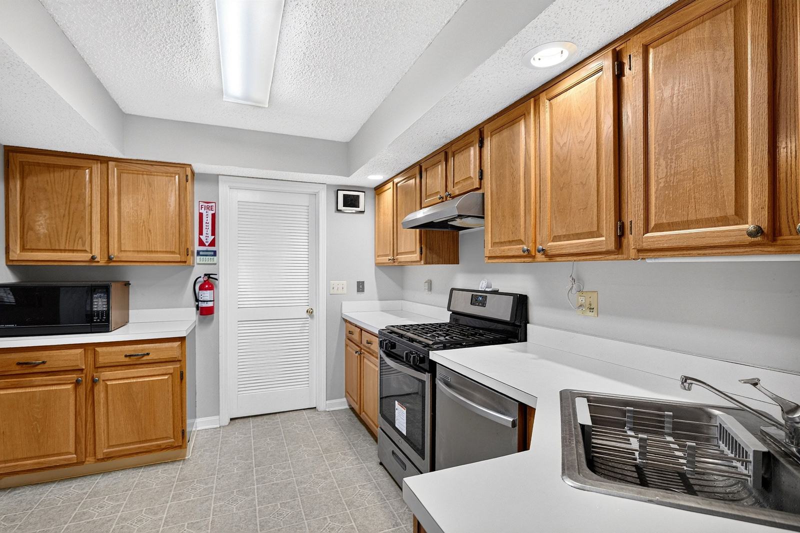 Galley kitchen with stainless steel gas range, dishwasher, sink and microwave