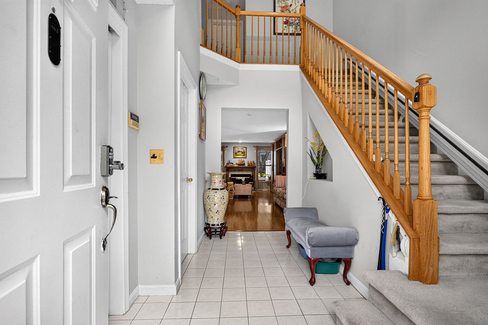 Two-story tiled foyer with an oak staircase and a view through to the fireplace